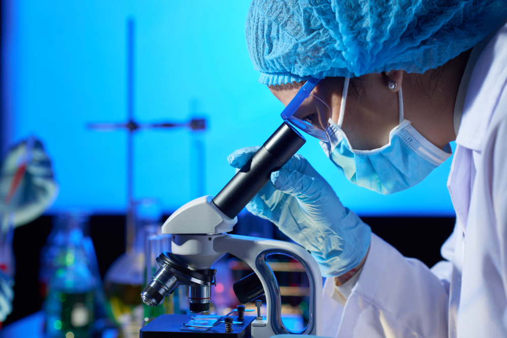 Mujer analizando una muestra a través de un microscopio